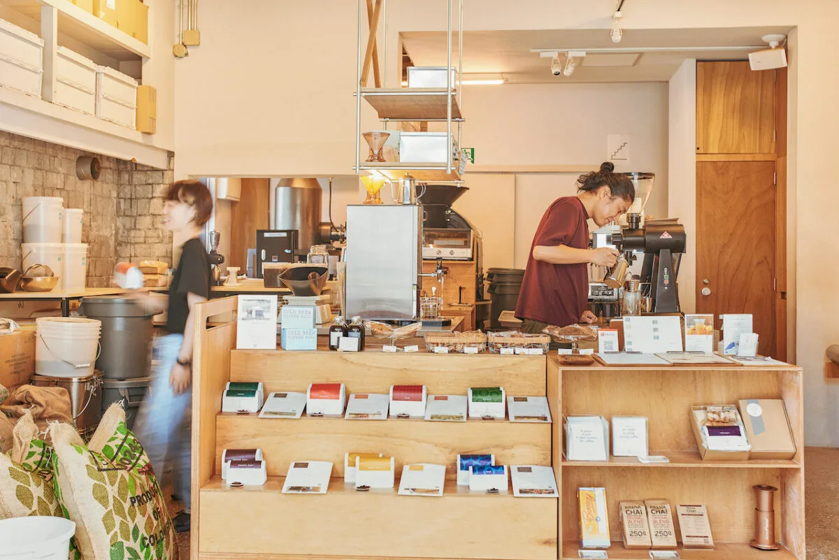 minimalist coffee shop with two baristas, wooden counters, and displayed products., coffee wrights kuramae, tokyo