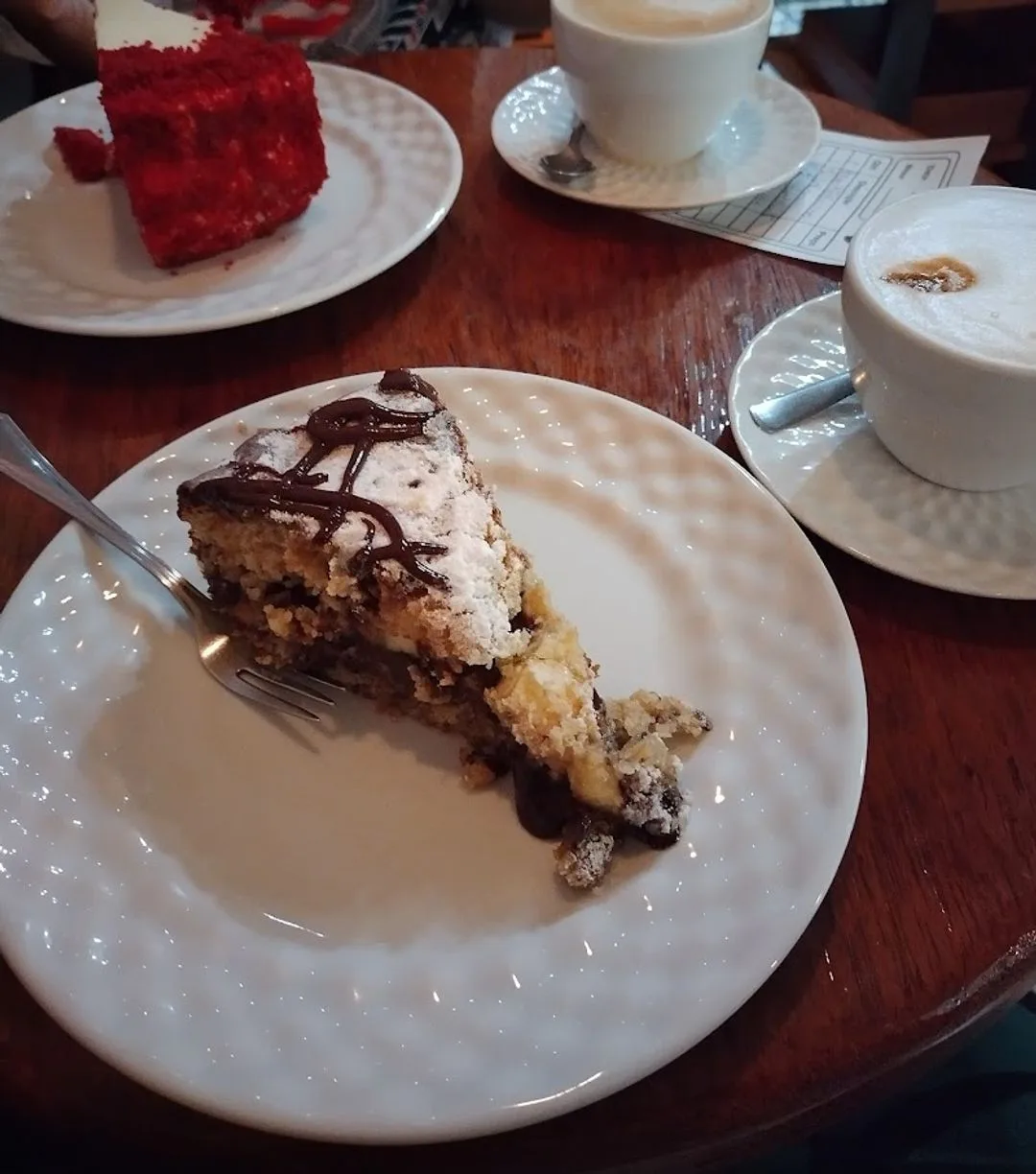 layered cake slice with whipped cream and chocolate drizzle, coffee cups, red velvet cake., coffeetown - plaza niterói, niter