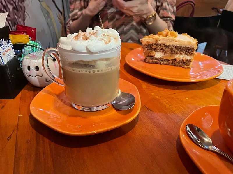 layered coffee drink with whipped cream and spice cake slice on orange plates., coffeetown - plaza niterói, niterói