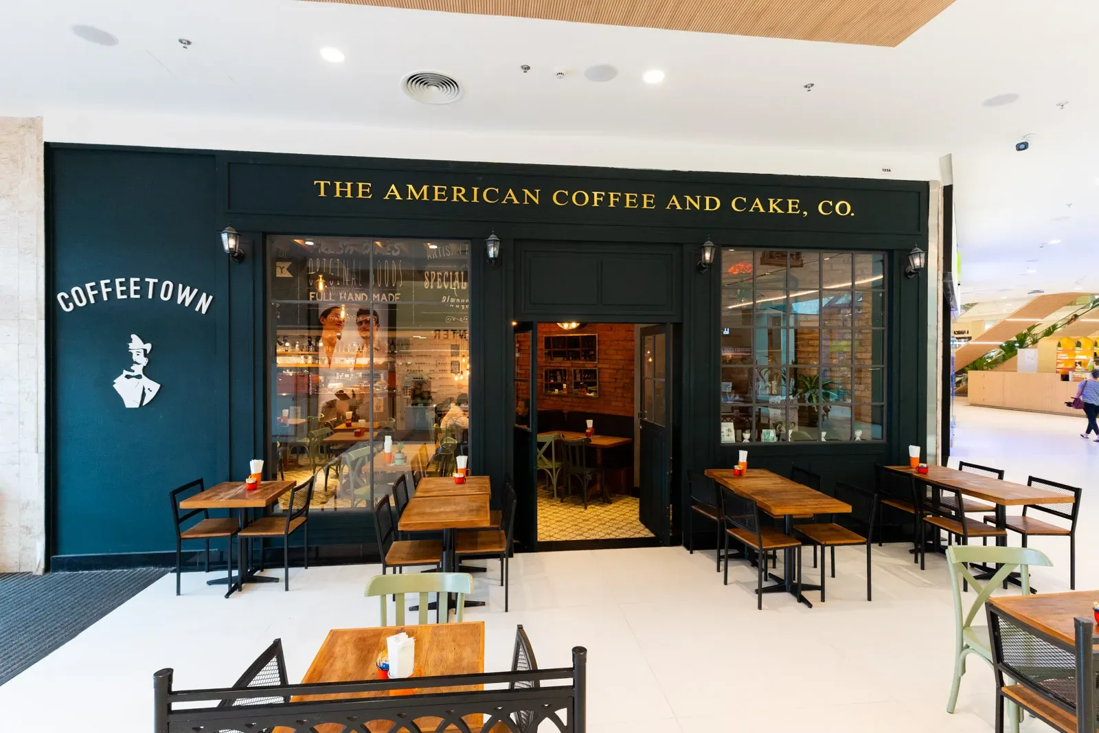 dark storefront café with wooden tables and vintage signage in mall setting., coffeetown, rio de janeiro