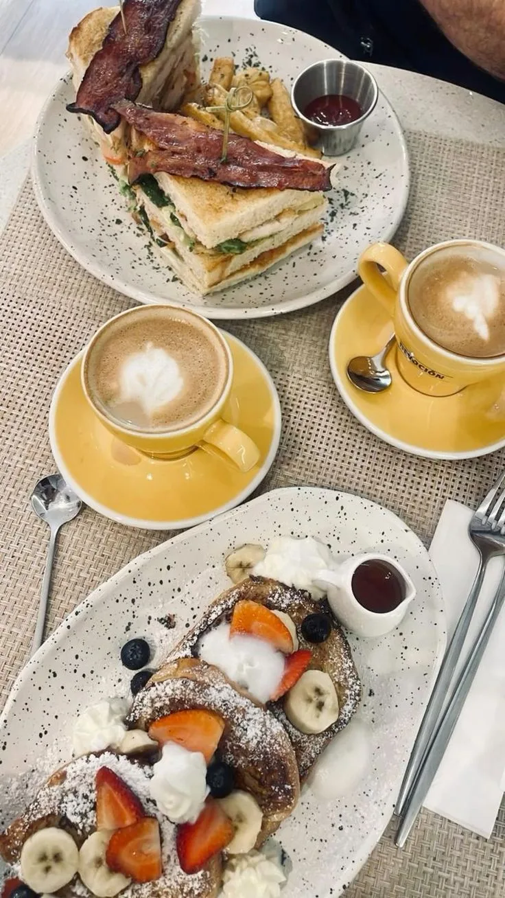 brunch spread with bacon sandwich, french toast, lattes, and berry compote., colibri café, cartagena