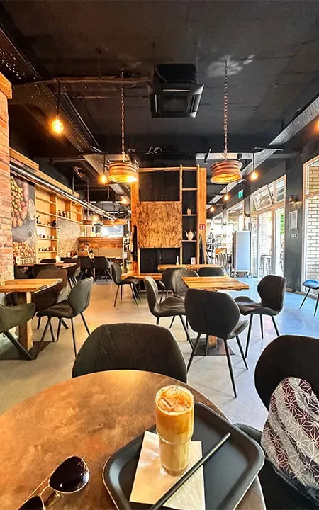 modern café interior with wooden tables, pendant lights, and black chairs throughout., cologne's roastery, cologne