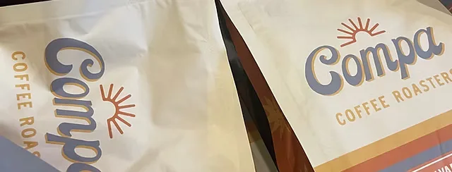compa coffee roaster branded packages with sun logo and text visible on white bags., compa coffee roasters, san diego