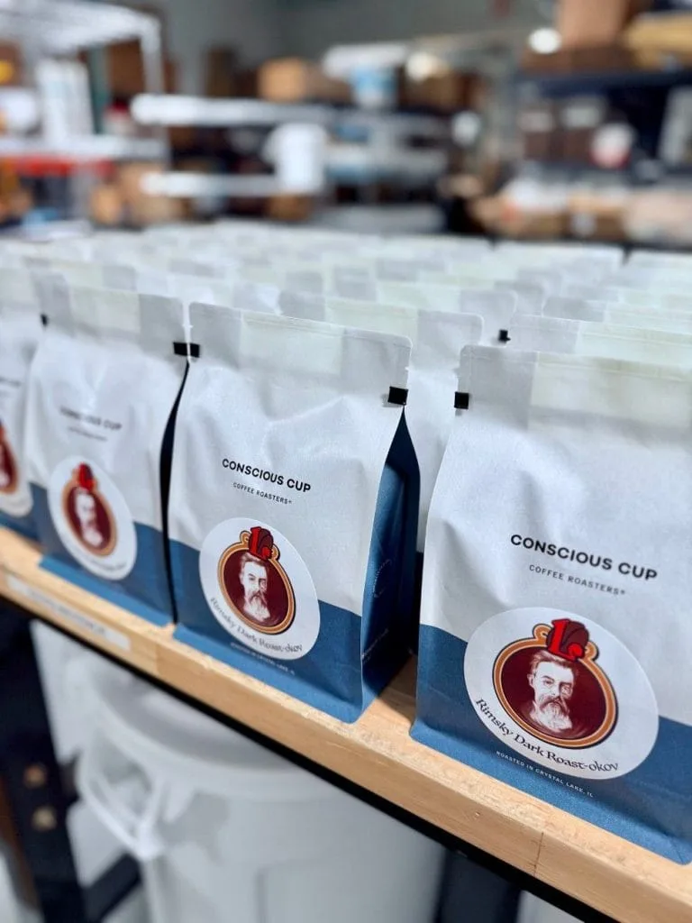 coffee bags from conscious cup coffee roastery lined up on wooden shelf., conscious cup coffee roasters - crystal lake, chica