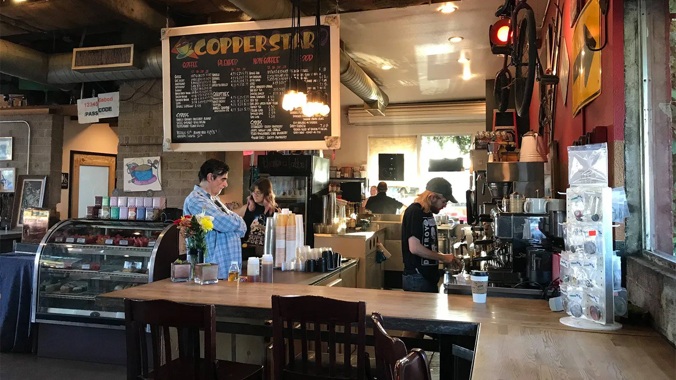 cozy coffee shop interior with menu board, baristas, customers, and bicycles on wall., copper star coffee, phoenix