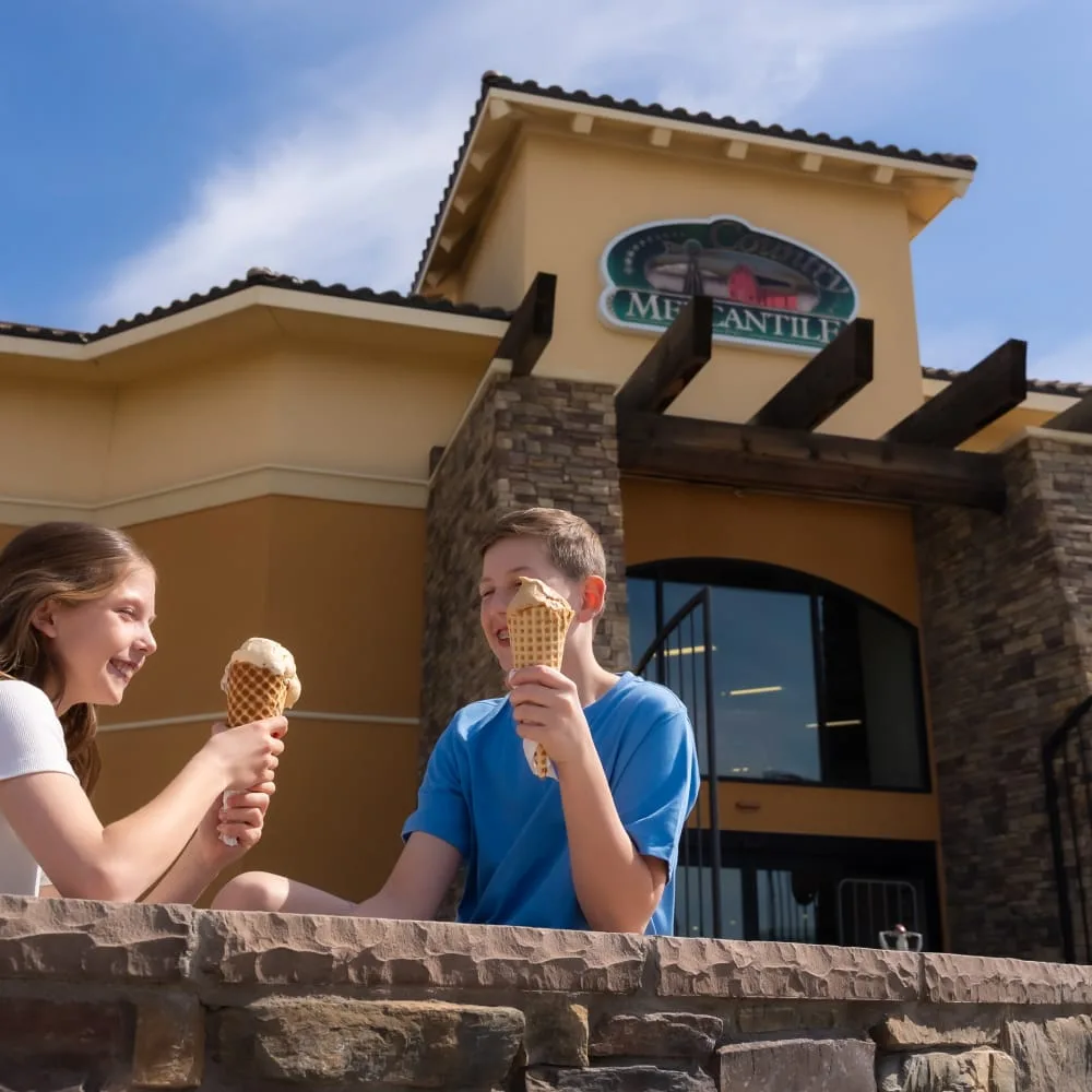 two children enjoying ice cream cones outside a creamery building on a sunny day., country mercantile, richland
