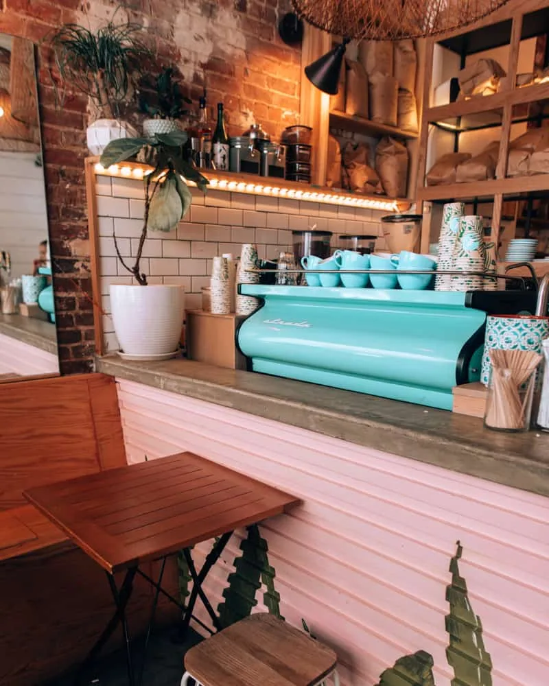 turquoise espresso machine in trendy café with pink counter and brick walls., cozy spot cafe, new york city