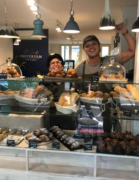 two staff members behind bakery counter displaying fresh pastries and baked goods., craft coffee & pastry amsterdam, amsterda