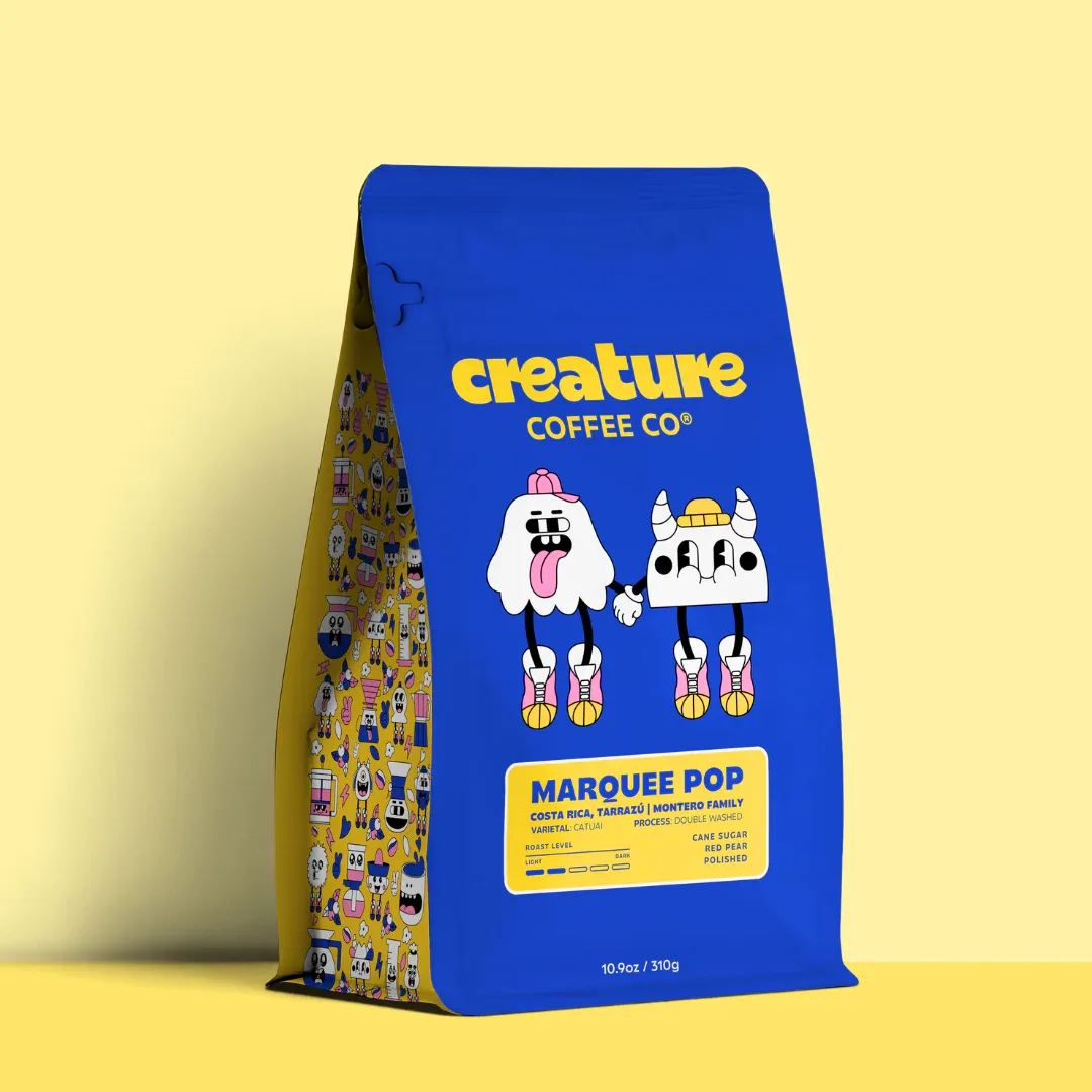 blue coffee bag with yellow branding, cartoon characters, and yellow patterned back panel., creature coffee co., austin