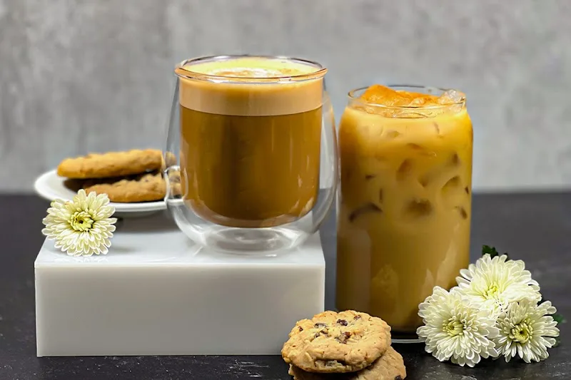 two coffee beverages with cookies and white flowers on white platform., crimson cup coffee shop - clintonville, columbus