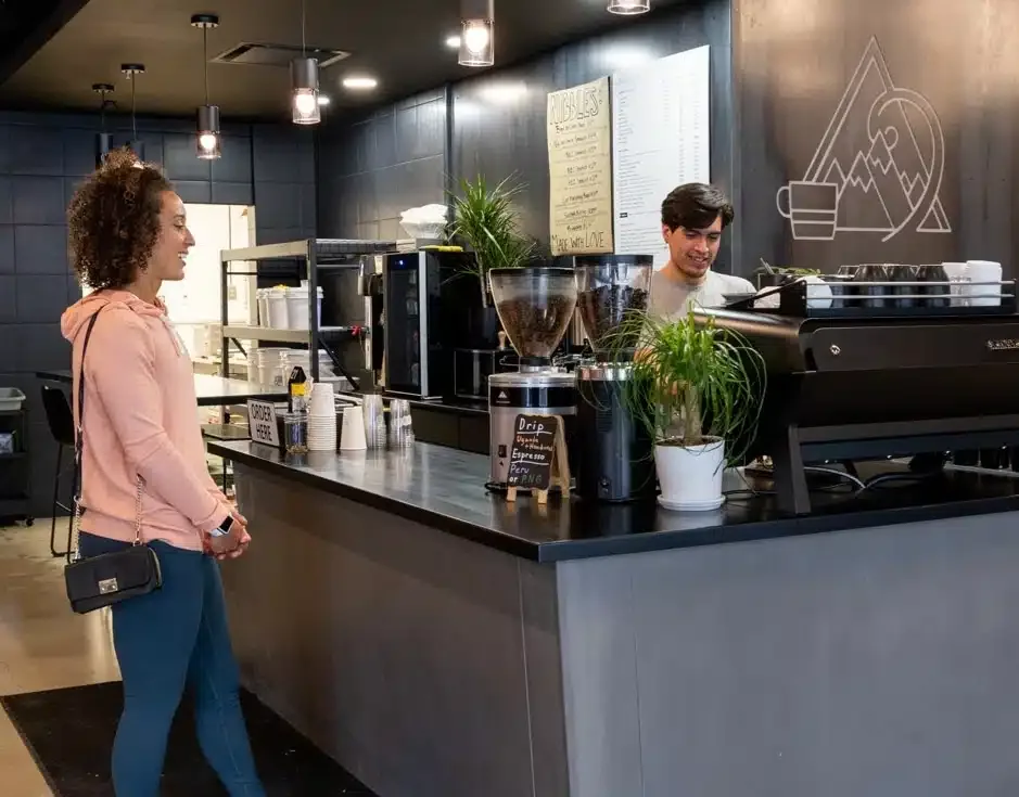 woman in pink jacket waits at modern coffee shop counter with barista., cupla coffee, salt lake city