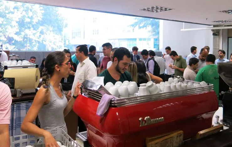 large red espresso machine with white cups, people gathered in modern office space., curto café, rio de janeiro