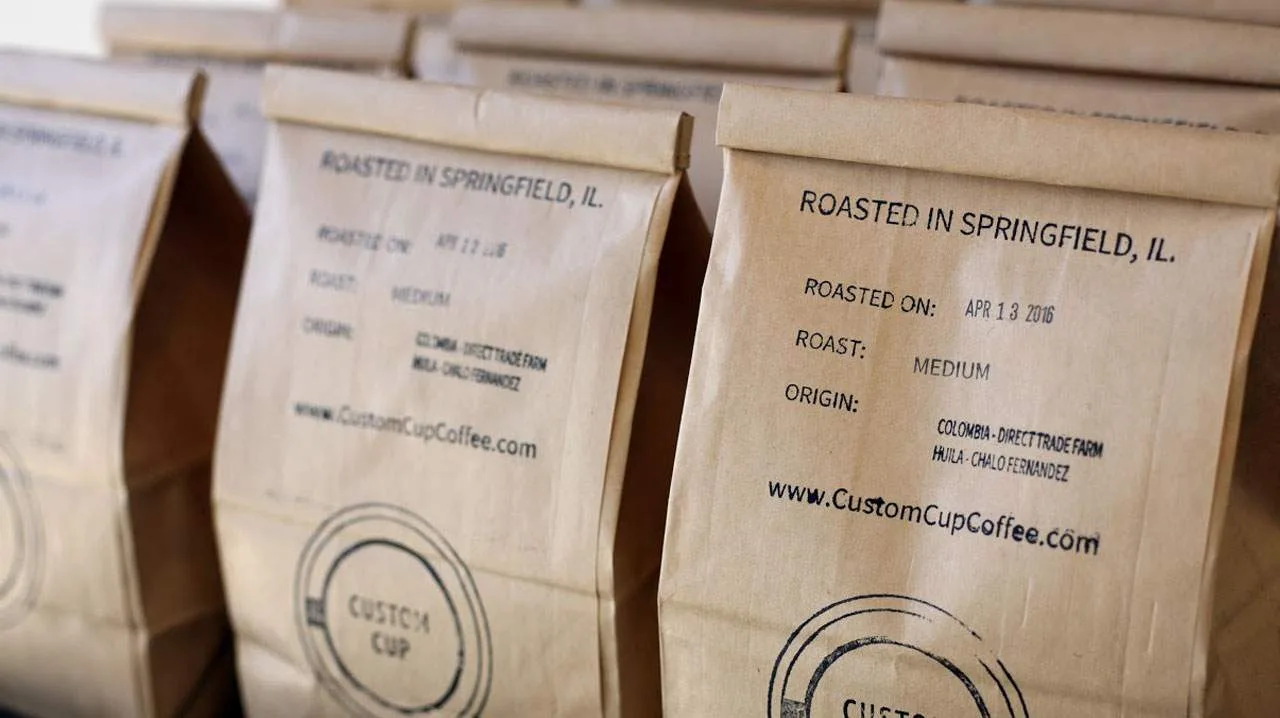coffee bags from custom cup coffee roasted in springfield, illinois with origin details printed on kraft paper., custom cup c