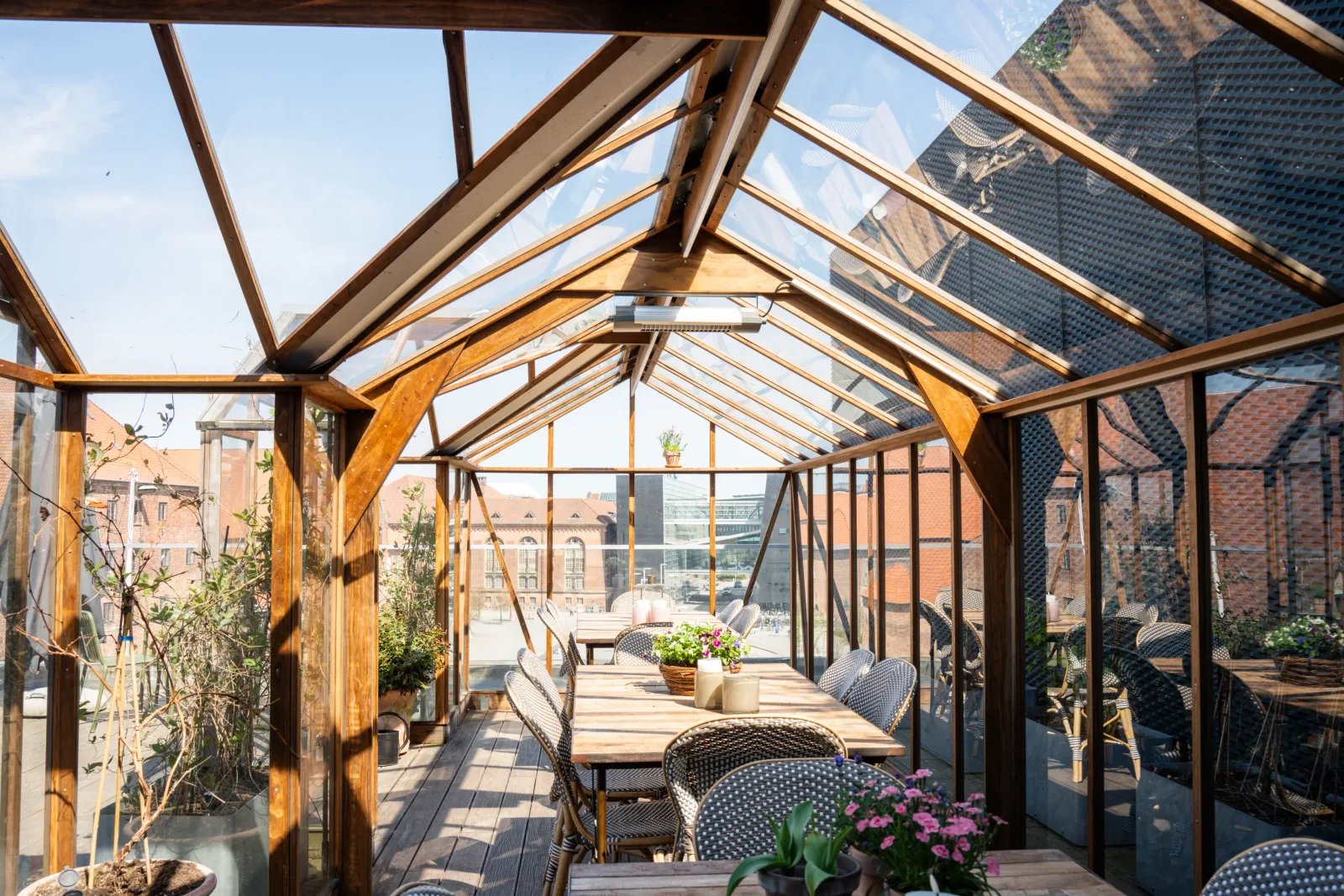 glass greenhouse conservatory with wooden beams, dining table, potted plants, urban rooftop., danish architecture center, cop
