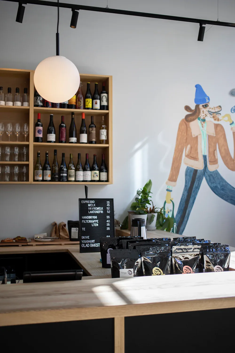 modern café counter with wine display, pendant lamp, and illustrated wall art., dapper, oslo