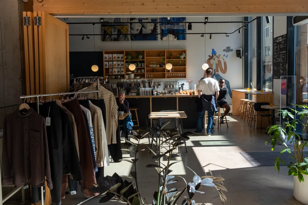 modern retail café space with clothing racks and wooden shelving displaying products., dapper, oslo
