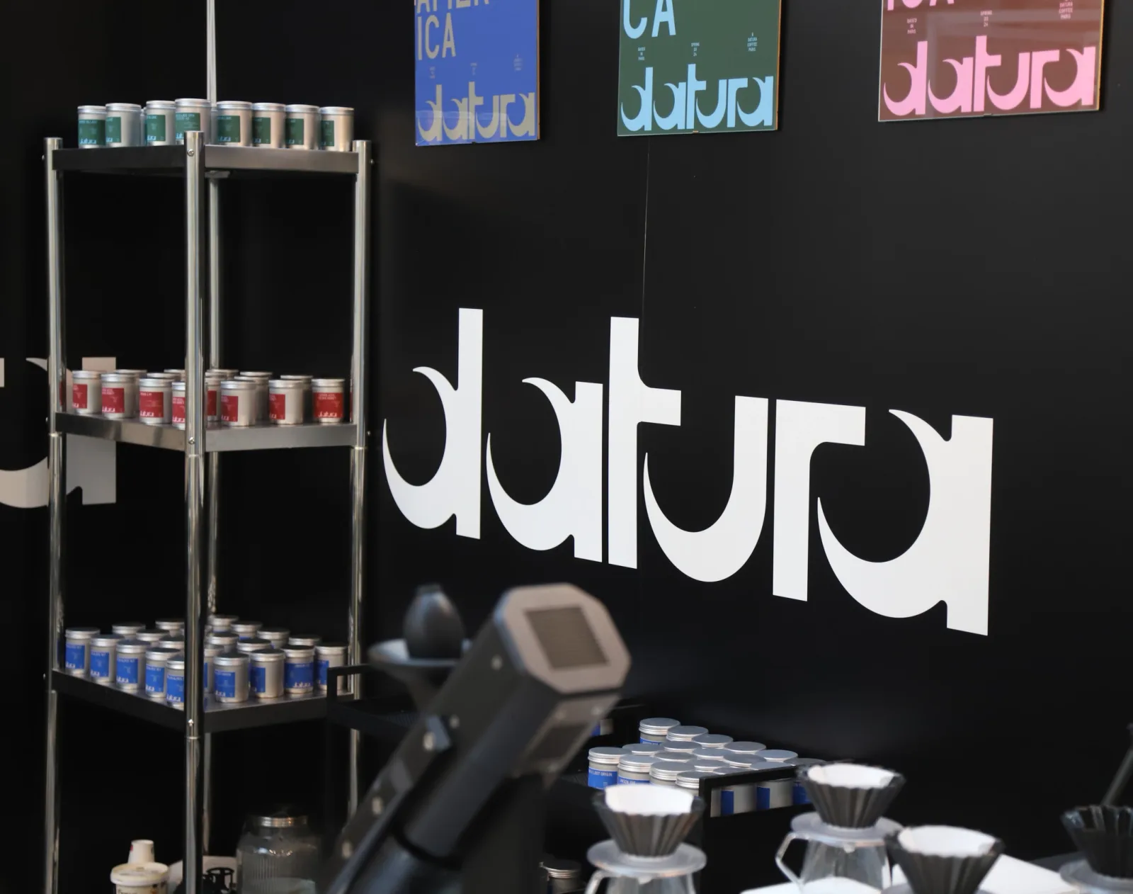 modern coffee shop display with shelving, products, and "aura" branding signage., datura, paris