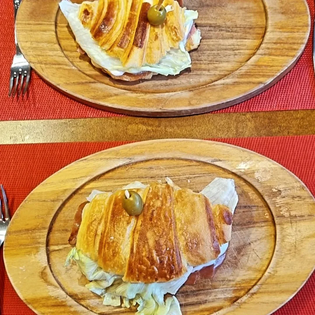 two wooden plates with sliced fish, green olives, and white garnish on red tablecloth., delicias madrid - croissant café curi