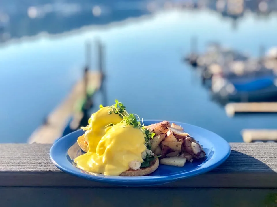 eggs benedict with hollandaise sauce overlooking coastal harbor and moored boats., devoted kiss cafe, gig harbor