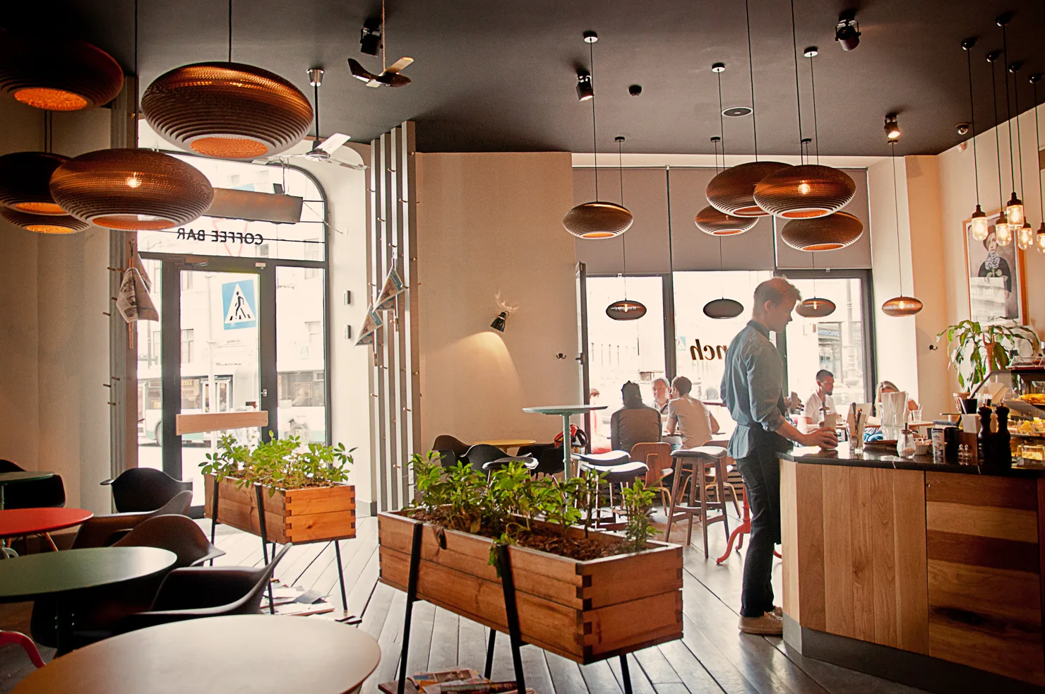 modern café interior with copper pendant lights and wooden planter boxes., dirty lights coffee company, st. petersburg