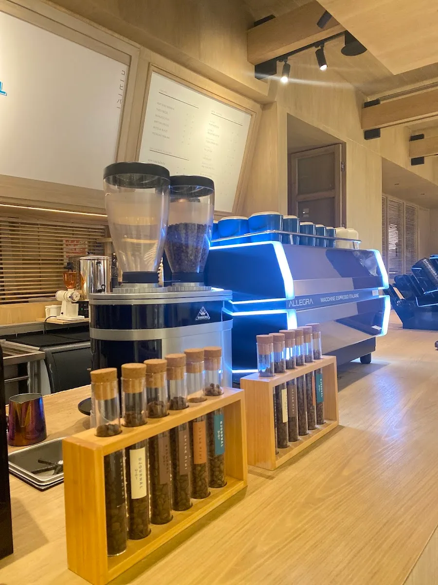modern espresso bar with blue machine, grinder, and coffee bean sample displays., djournal coffee at cafe kissa, jakarta