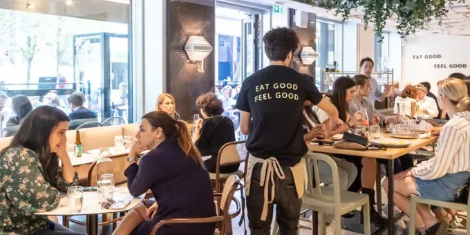 busy casual restaurant with diners seated at tables, staff wearing "eat good feel good" shirts., ds café, paris