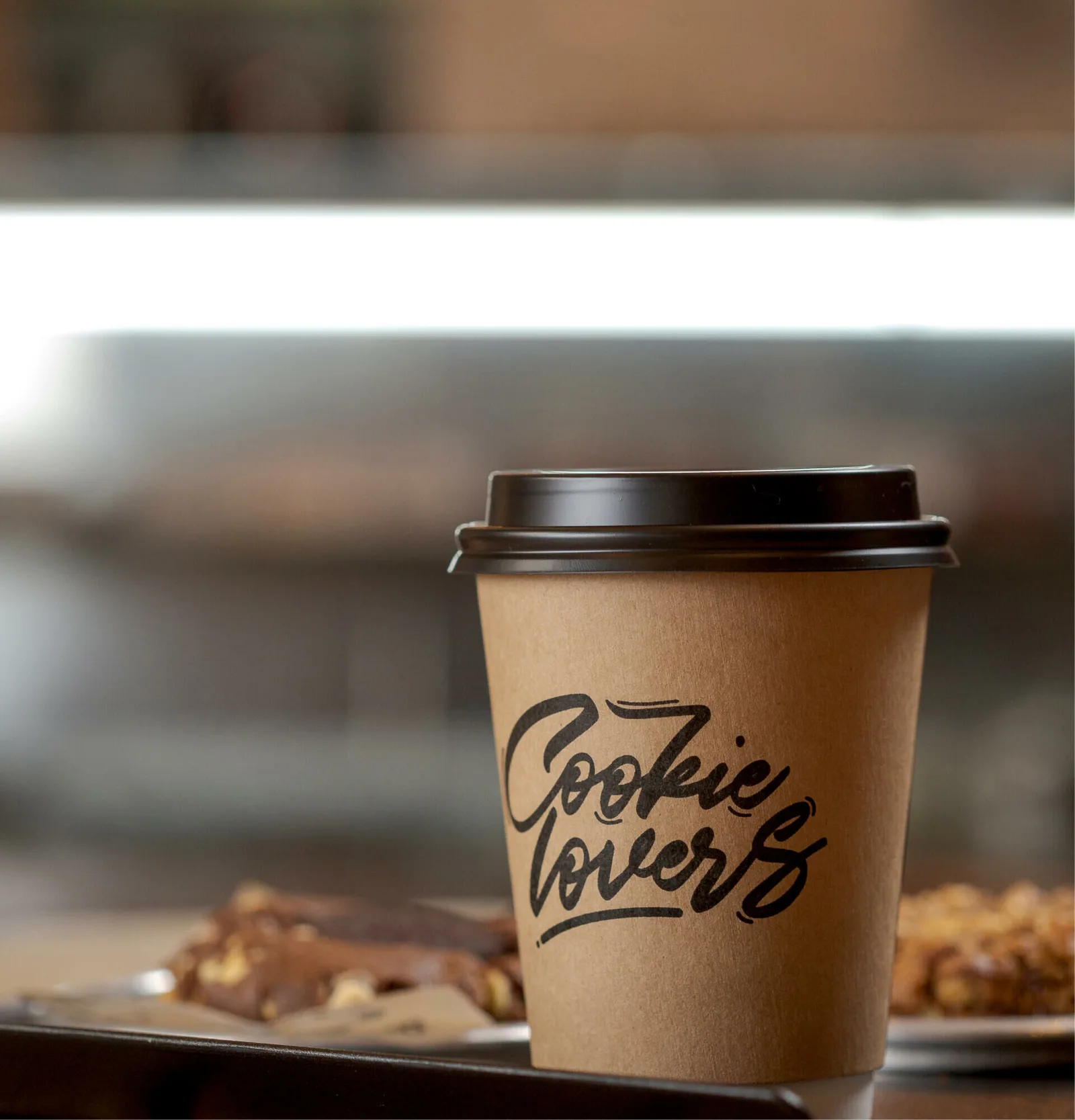 cookie lovers café cup with brown lid and fresh baked cookies nearby., duckbill - cookies & coffee, rio de janeiro