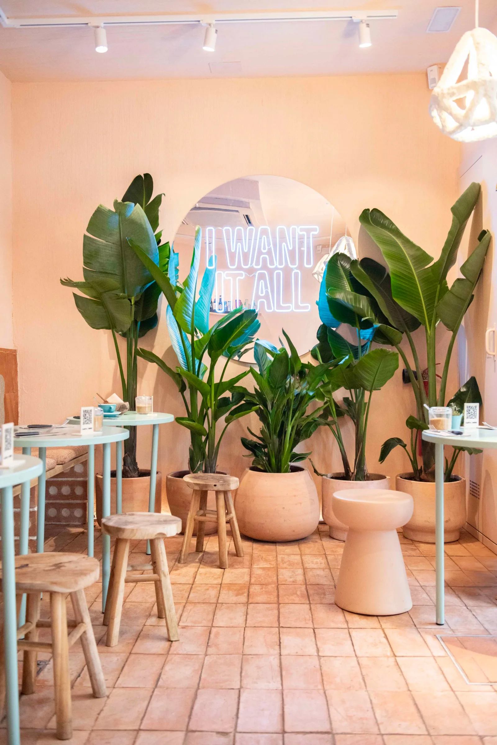 warm peachy cafe interior with lush green plants and neon signage., eatmytrip specialty coffee & brunch barcelona, barcelona