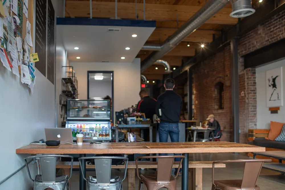 modern coffee shop interior with wooden table, laptop, and customers at counter., ebrik coffee room, georgia