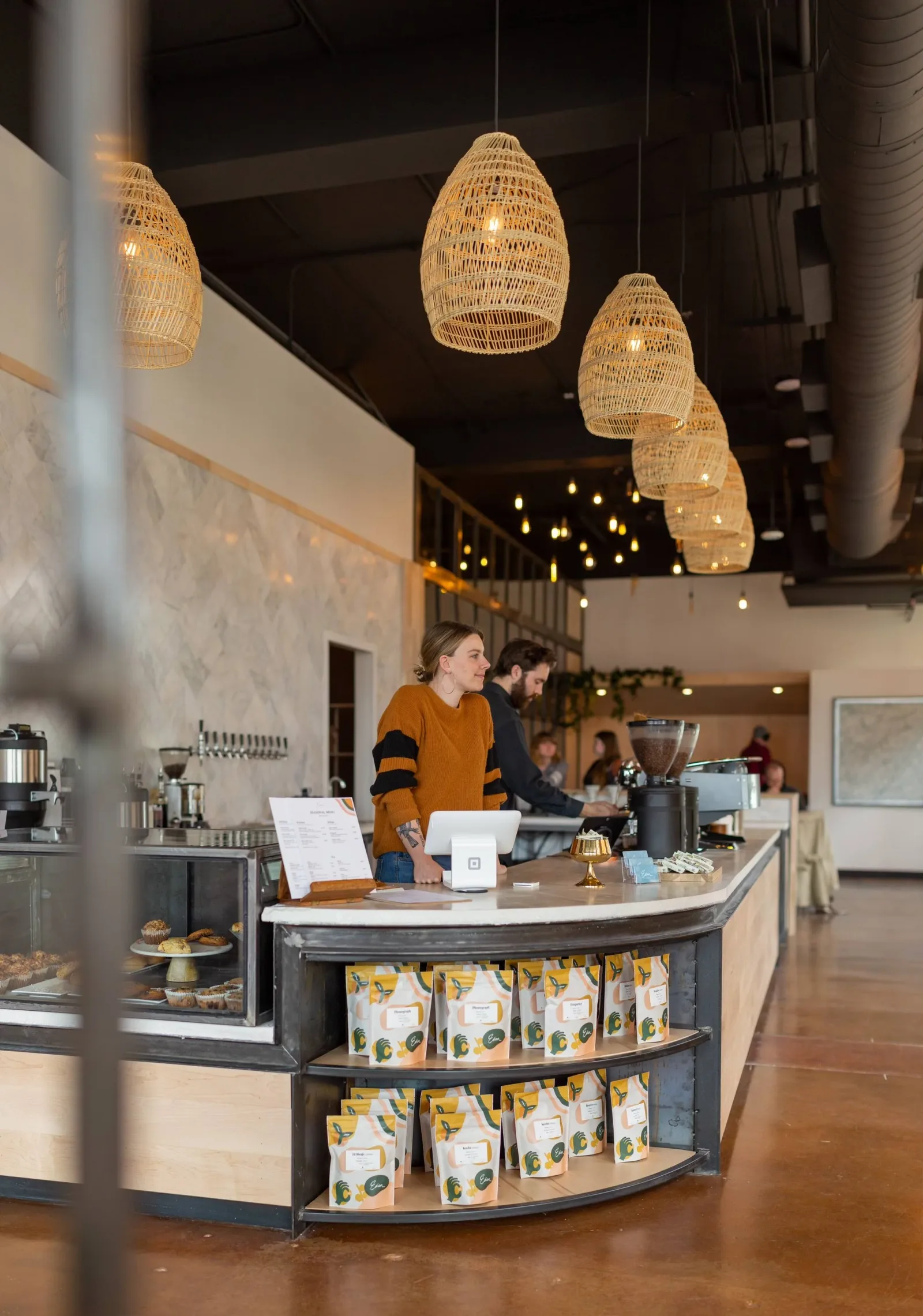 modern café interior with woven pendant lights and curved counter display., edison coffee co roastery, lewisville