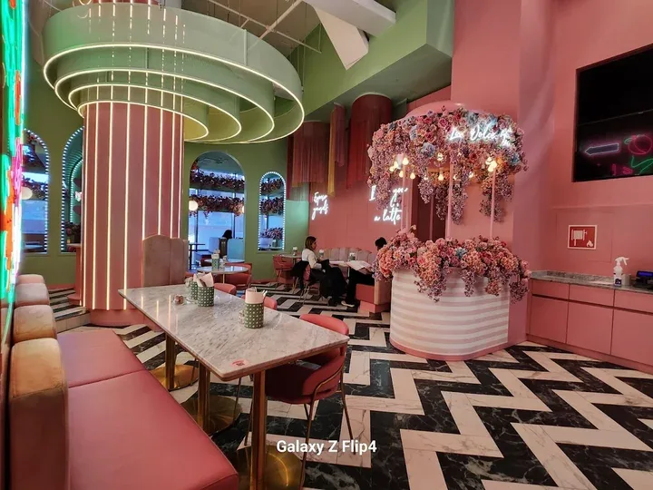 modern pink and green cafe with neon lighting, marble table, and floral installation., el&n gae aulenti, milan