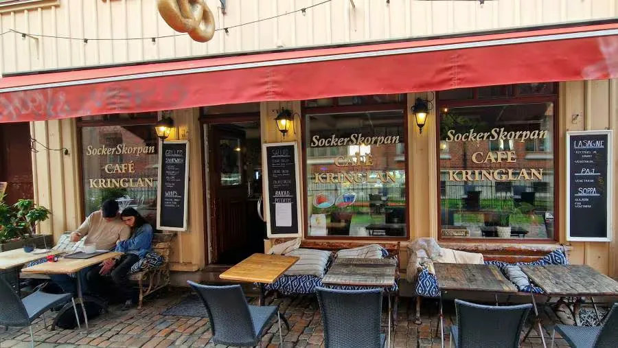 scandinavian café storefront with outdoor seating and decorative blue cushions., en deli haga, gothenburg