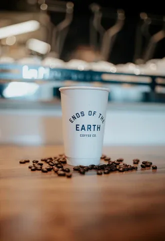 coffee cup with "ends of the earth" logo surrounded by scattered coffee beans., eote coffee, oklahoma city