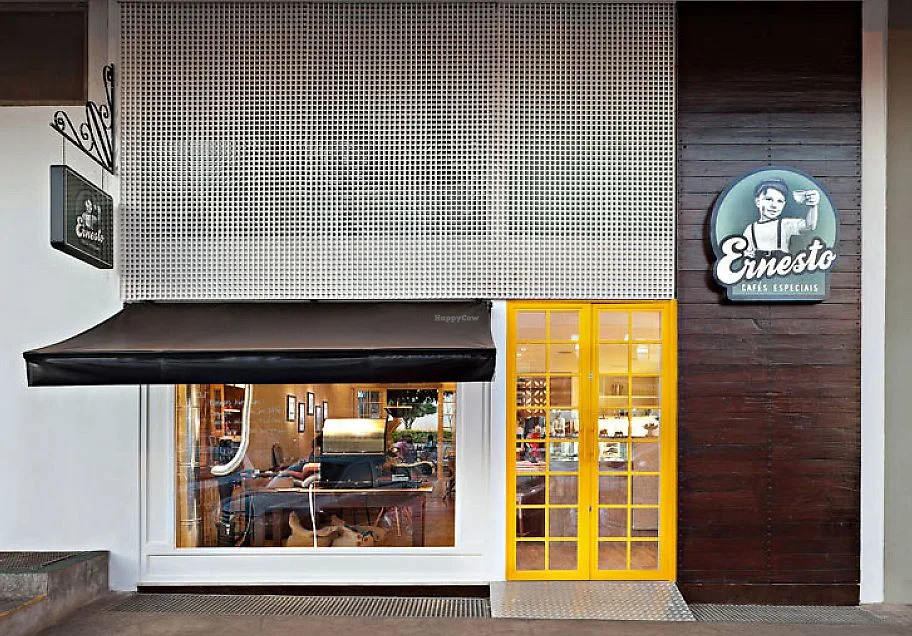 ernesto café storefront with yellow doors, black awning, and vintage signage., ernesto cafés asa norte, brasília