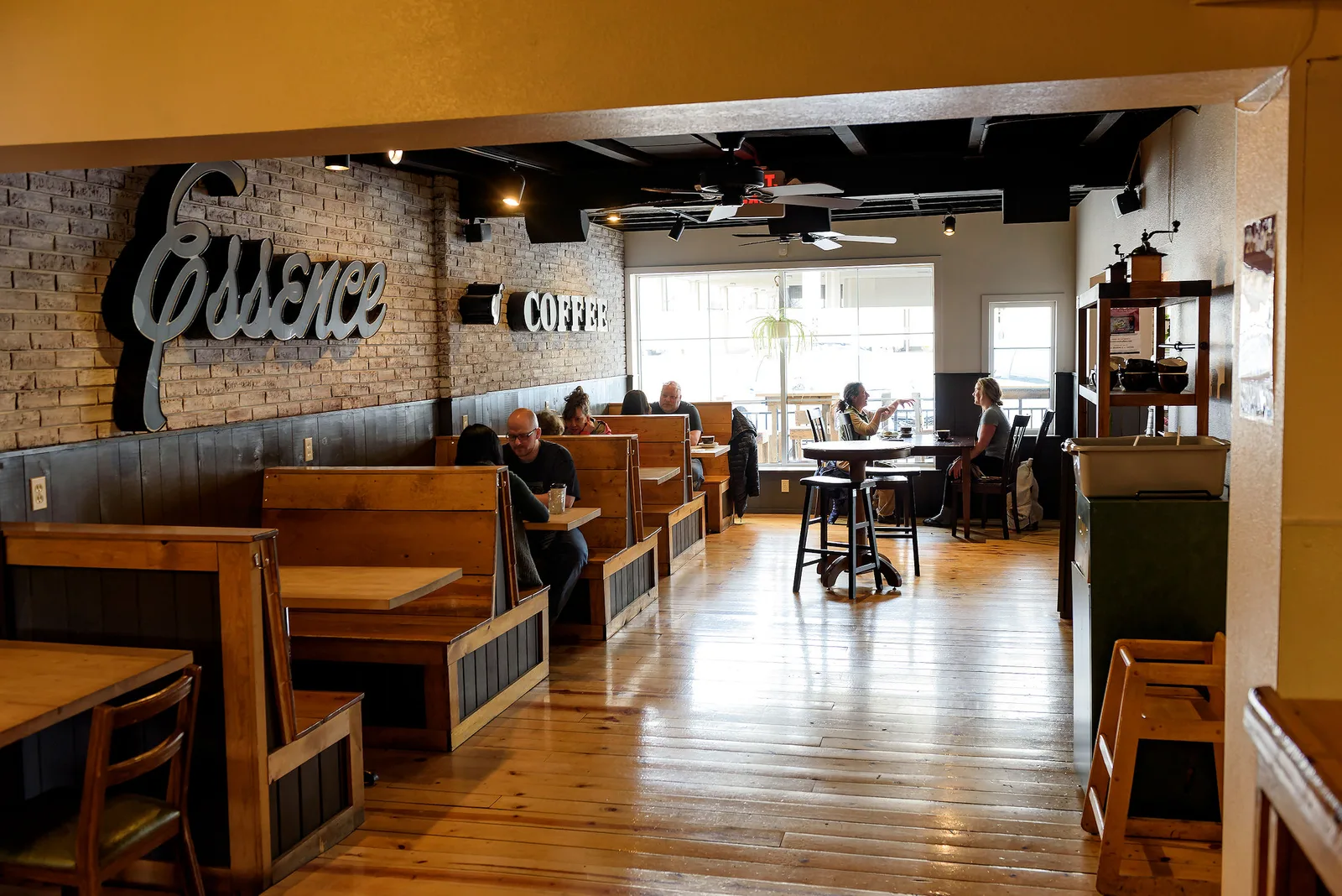 coffee shop interior with wooden booths, brick wall, and seated customers., essence of coffee, rapid city