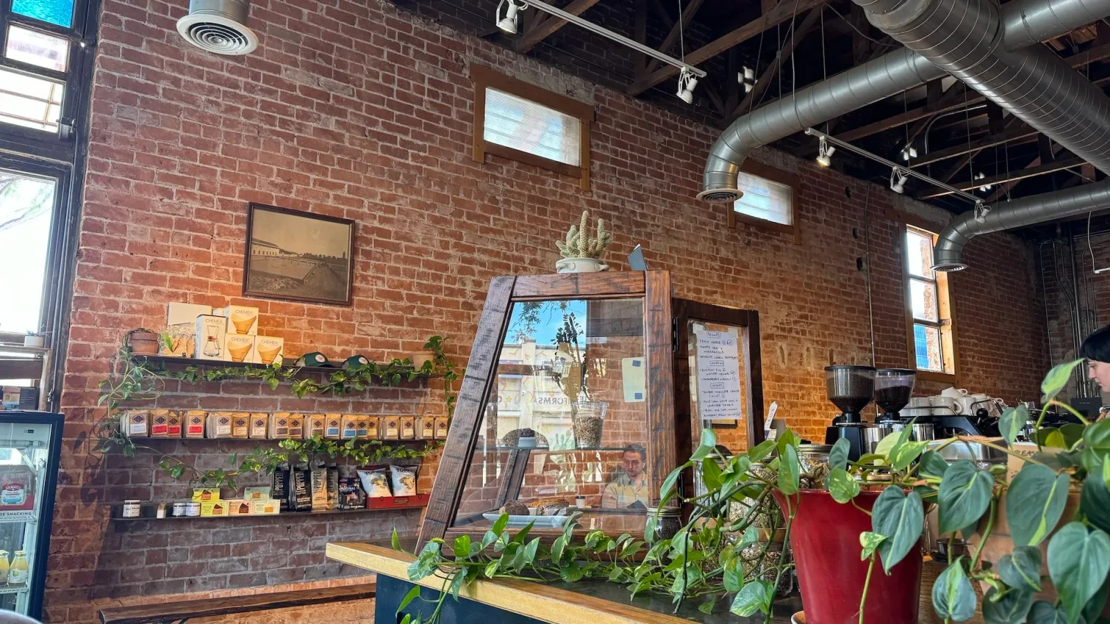 modern coffee shop interior with exposed brick walls and industrial ductwork overhead., exo roast co, arizona