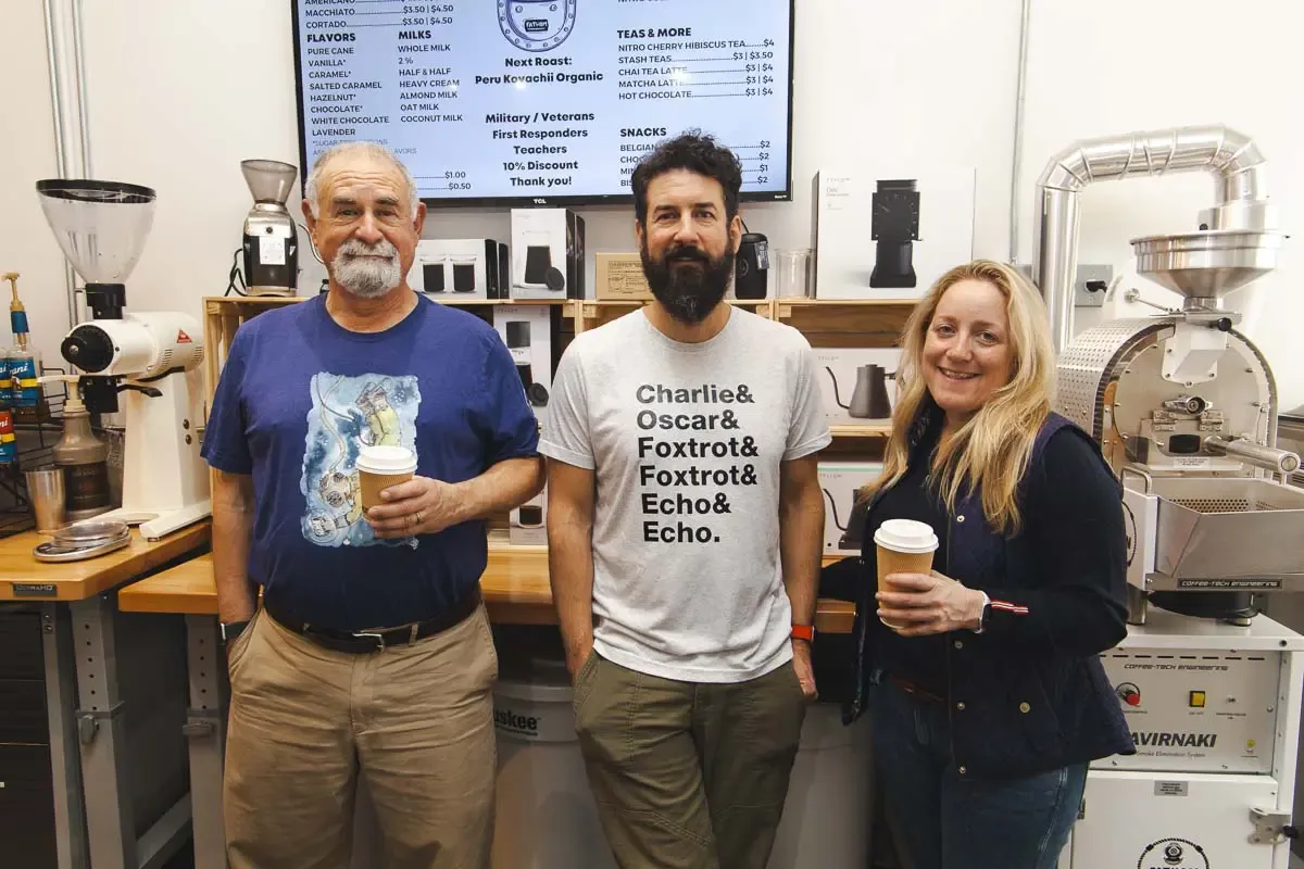 three people standing in coffee shop holding beverages, professional equipment visible behind them., fathom coffee, virginia 