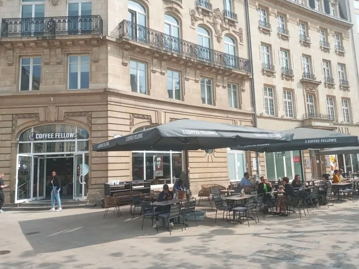 parisian café with black umbrellas, outdoor seating, historic stone architecture., fellows, paris