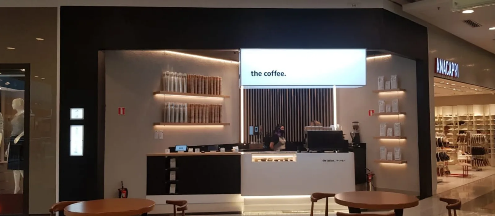 modern minimalist coffee shop interior with illuminated shelving and "the coffee" signage above counter., festval parkshoppin