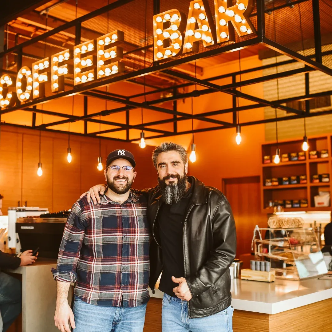 two bearded men smiling inside a bakery with illuminated sign overhead., fidel & co coffee roasters, little rock