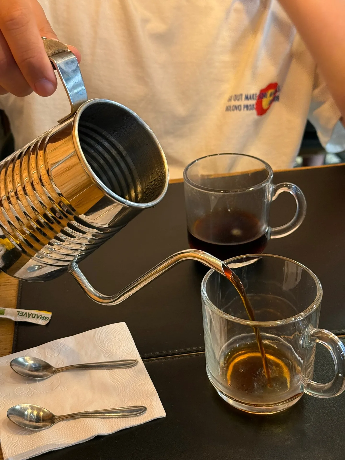 hand pouring dark coffee from bamboo thermos into glass mugs at table., fillmore ipiranga, são paulo