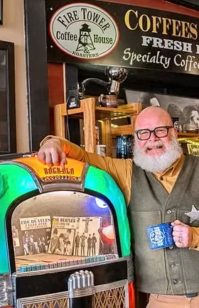 man with beard and glasses posing next to vintage jukebox in coffee shop., firetower coffee house, montana