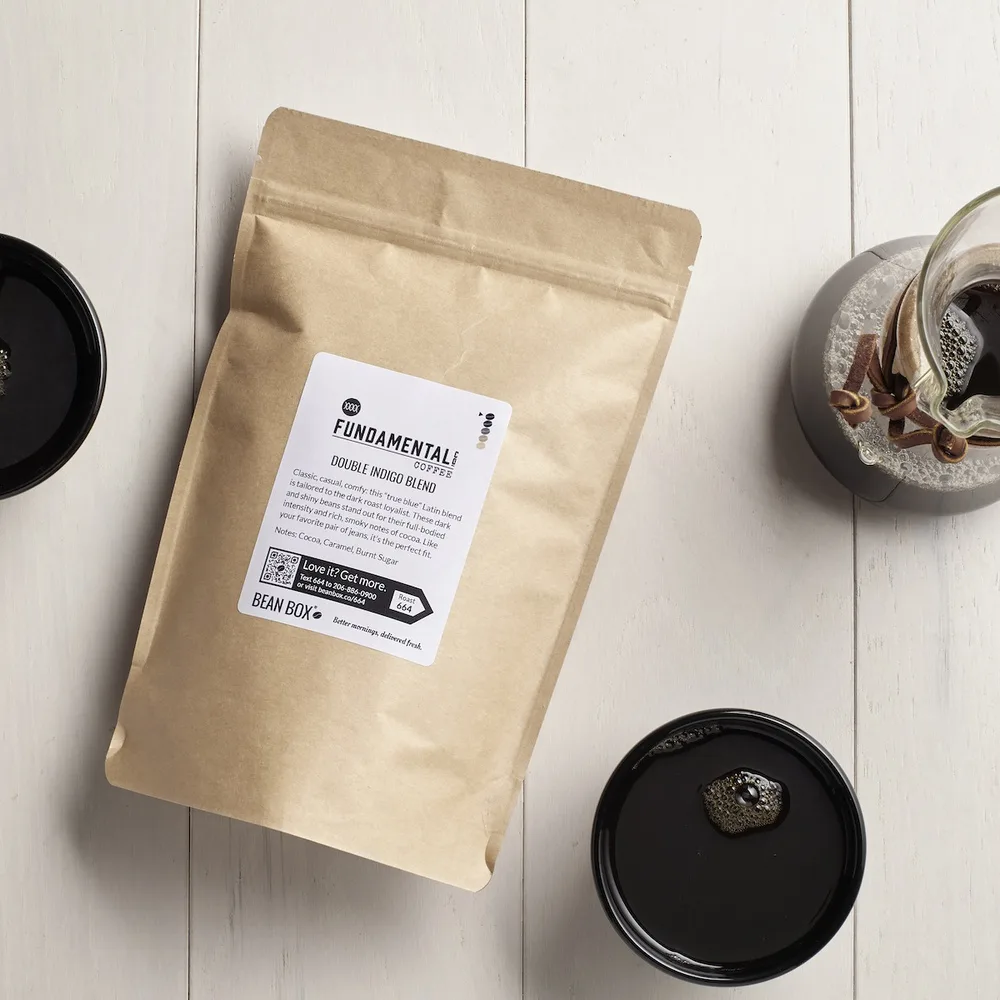 kraft coffee bag with label surrounded by black cups and brewed coffee on white wood., fitzco coffee roasters, new york city