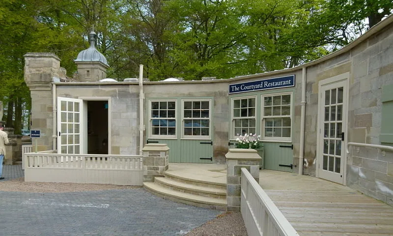 stone restaurant building with green doors and white-framed windows surrounded by trees., floors castle, newtown st boswells