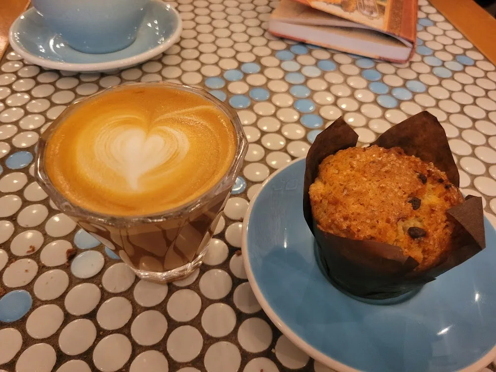 latte with heart latte art and chocolate chip muffin on geometric tile table., flux coffee, oyster bay