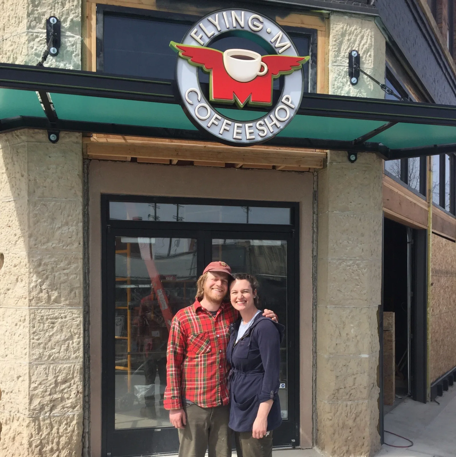 two people standing outside flying m coffeeshop entrance, smiling at camera., flying m coffeeshop, nampa