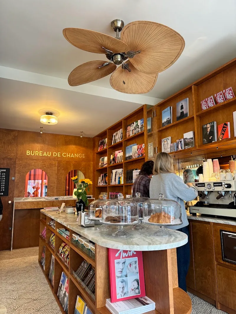 boutique café with wooden shelving, petal-shaped ceiling fan, marble counter., foreign exchange news, london
