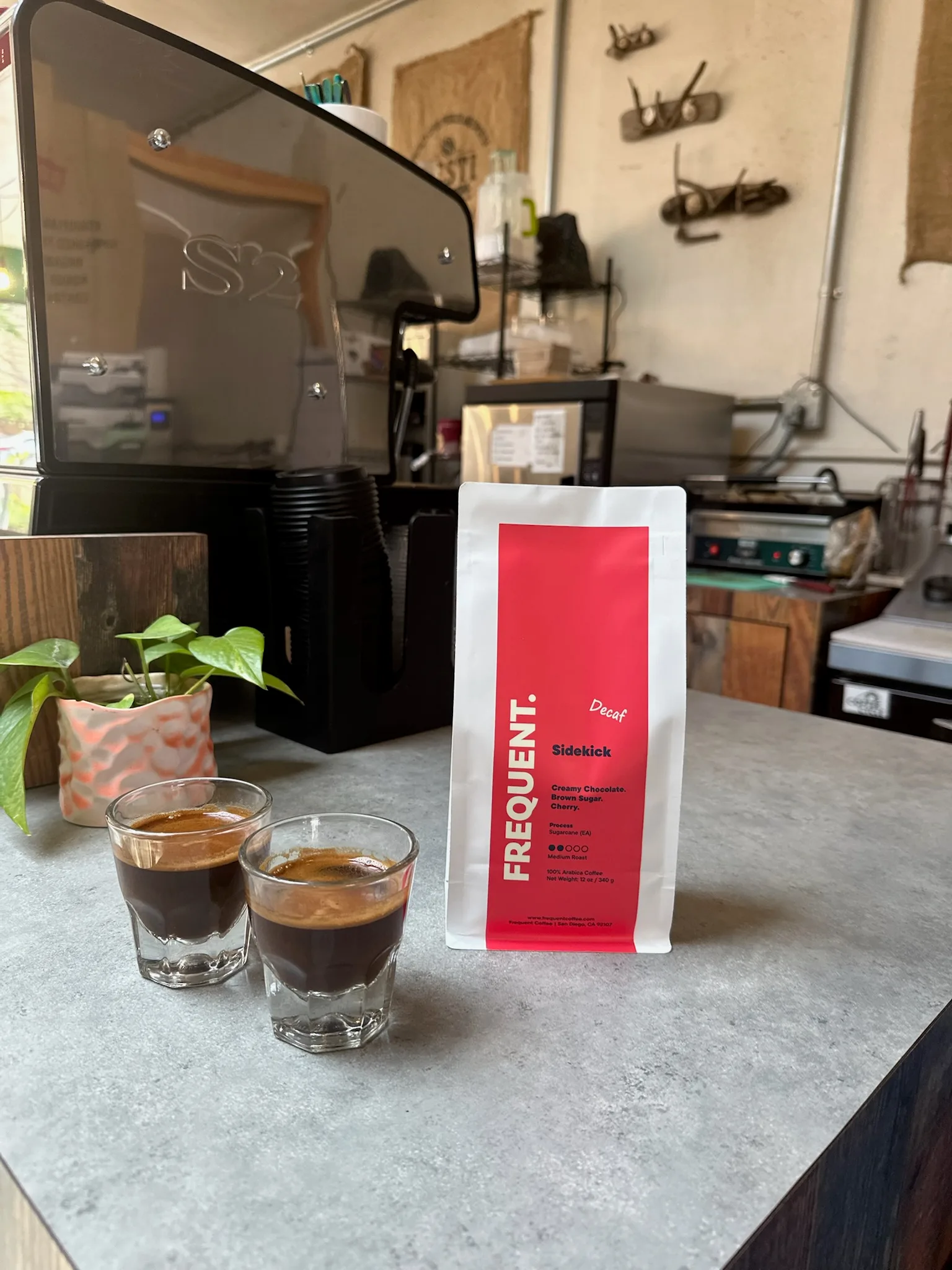 two espresso shots beside freqeunt coffee bag in maker's workspace., frequent coffee, san diego