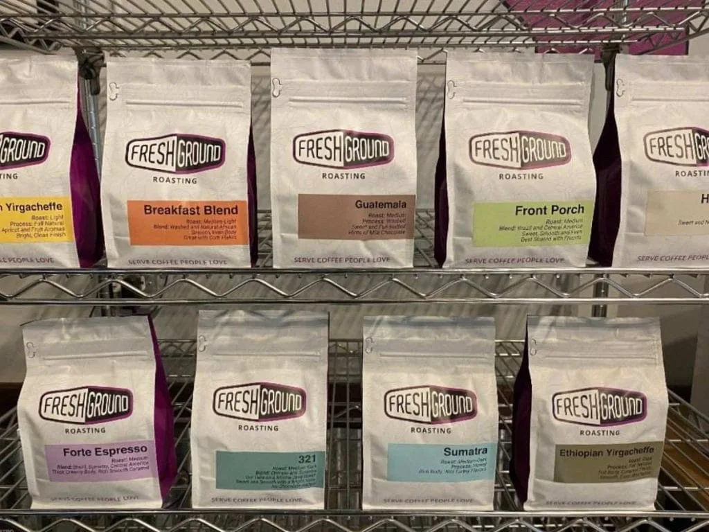 fresh ground coffee bags displayed on wire shelves, various roasts and origins., fresh ground roasting, illinois
