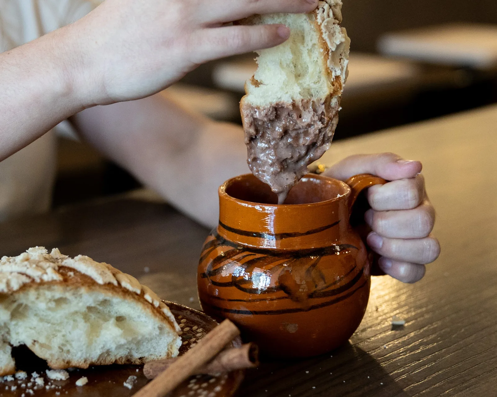 child's hand dipping bread into decorative ceramic pot of spread., frida's coffee home, calgary